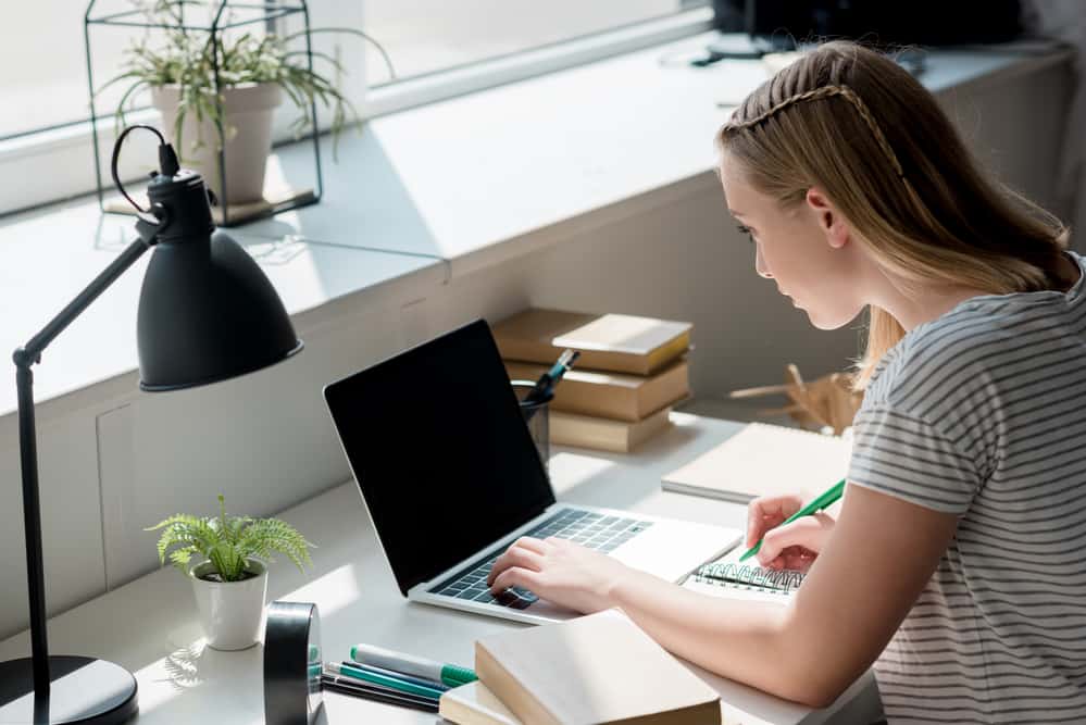 Концентрований підліток студент дівчина працює з ноутбуком вдома